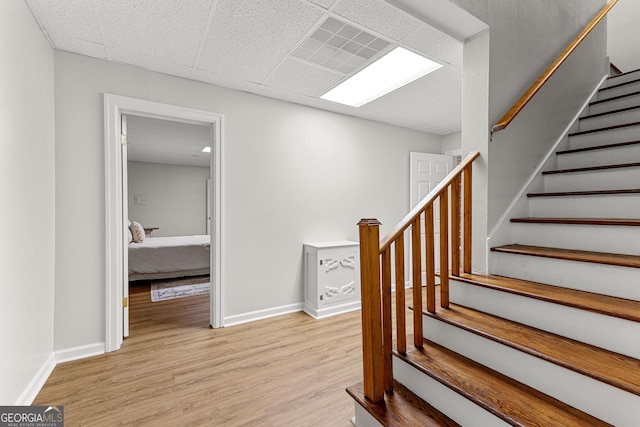 stairway featuring a drop ceiling, wood finished floors, visible vents, and baseboards