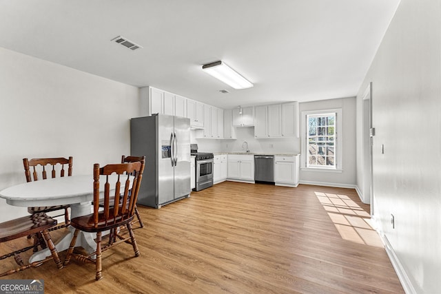 kitchen with visible vents, white cabinets, light wood-style flooring, appliances with stainless steel finishes, and light countertops