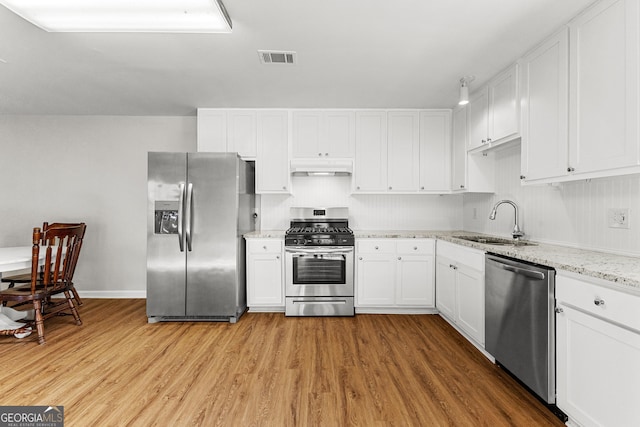 kitchen featuring under cabinet range hood, appliances with stainless steel finishes, white cabinets, and a sink
