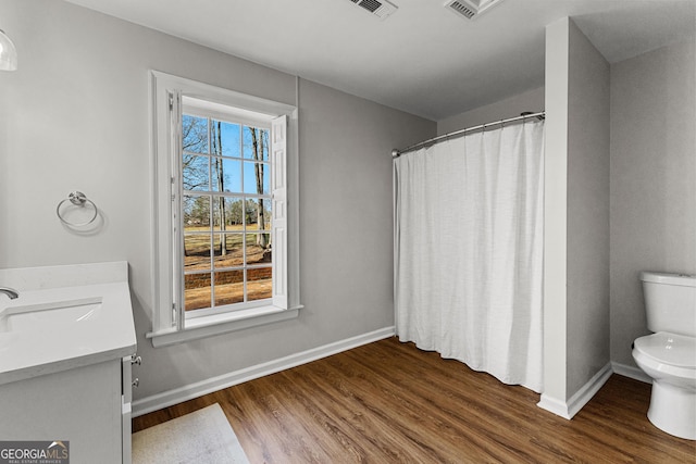 full bathroom featuring plenty of natural light, vanity, toilet, and wood finished floors