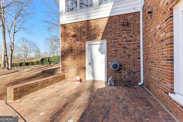 property entrance with a patio and brick siding