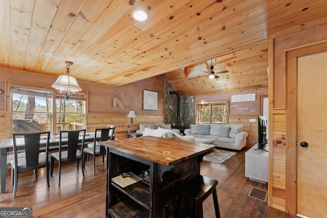 dining room featuring a healthy amount of sunlight, dark wood-style floors, wood ceiling, and vaulted ceiling