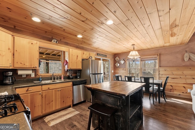 kitchen with pendant lighting, dark wood finished floors, stainless steel appliances, light brown cabinetry, and a sink