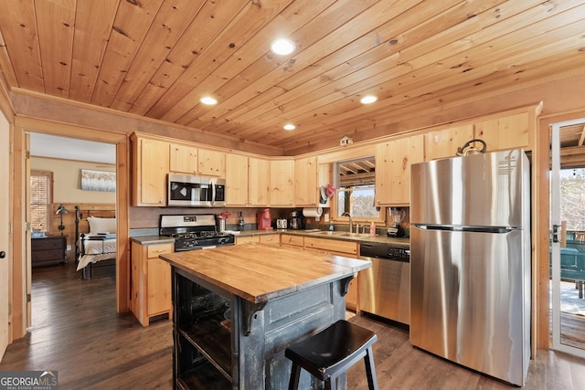 kitchen with a center island, appliances with stainless steel finishes, dark wood-type flooring, light brown cabinets, and wood counters