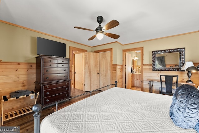 bedroom featuring crown molding, wooden walls, wood finished floors, and wainscoting