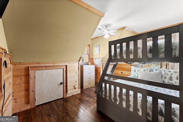 bedroom featuring vaulted ceiling, dark wood-type flooring, wood walls, and a wainscoted wall