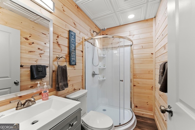 full bathroom featuring a stall shower, toilet, wooden walls, and vanity