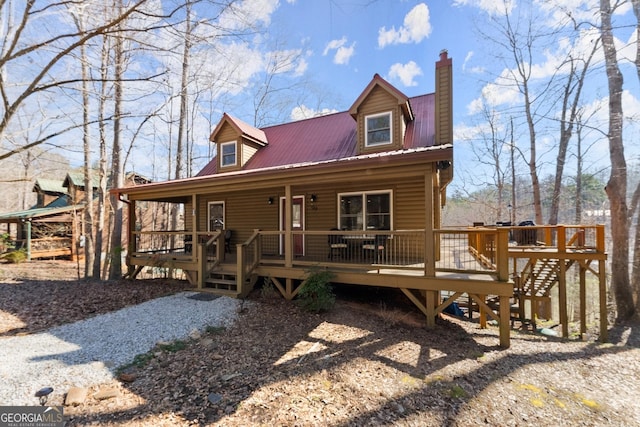 view of front of home with a deck, metal roof, and a chimney