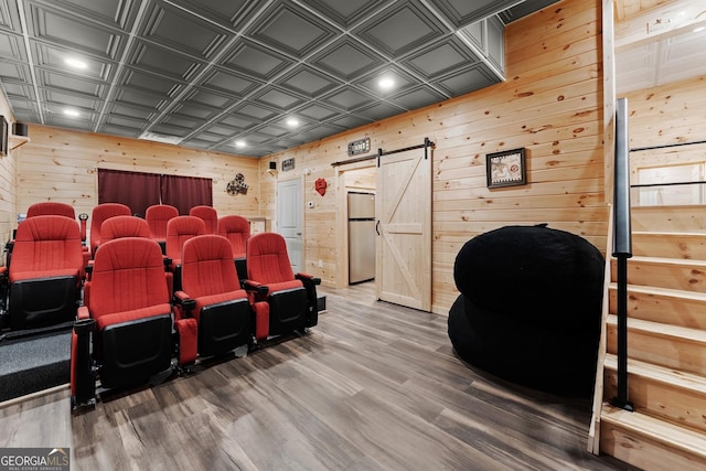 home theater with an ornate ceiling, recessed lighting, a barn door, wooden walls, and wood finished floors