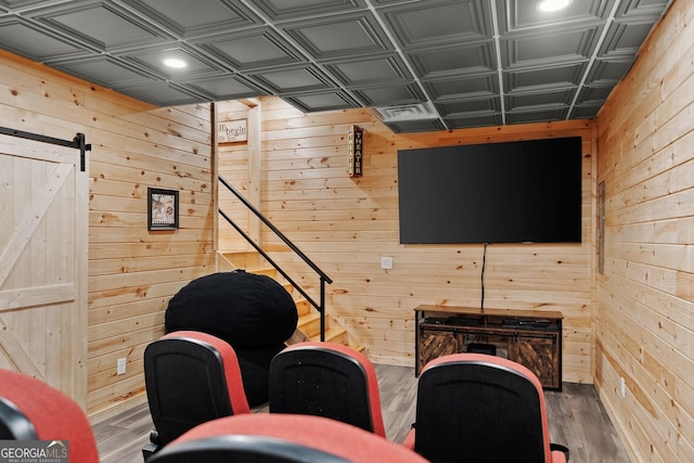 interior space with an ornate ceiling, a barn door, wooden walls, and wood finished floors