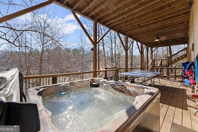 wooden terrace with ceiling fan, a hot tub, and stairs