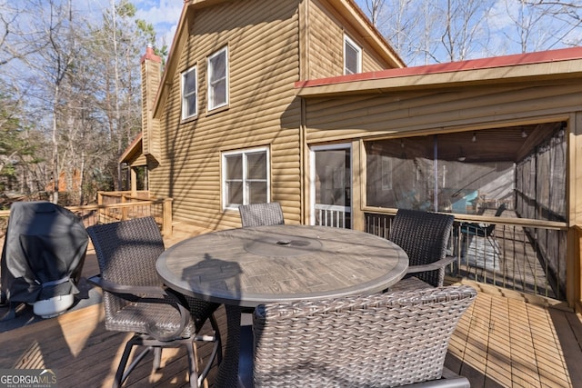 wooden terrace with a grill and outdoor dining area