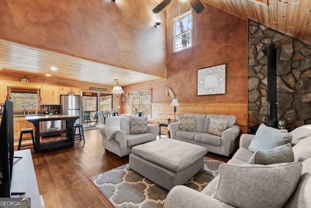 living area with a wood stove, wooden ceiling, a wealth of natural light, and dark wood-style flooring