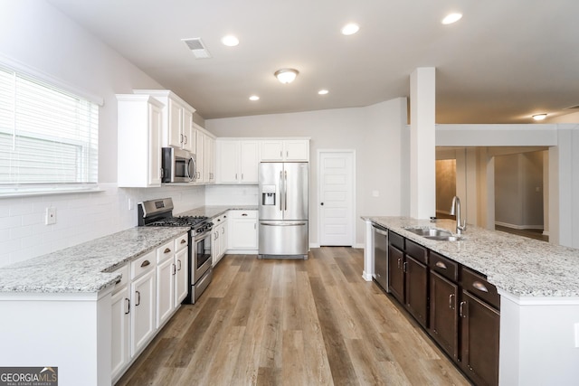 kitchen featuring white cabinetry, appliances with stainless steel finishes, light stone counters, and a sink