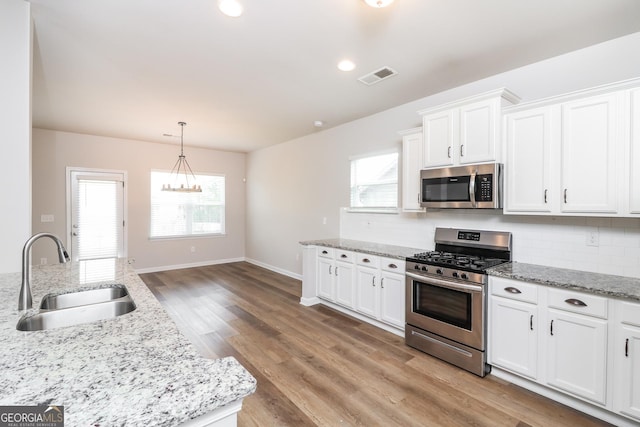 kitchen with visible vents, decorative backsplash, stainless steel appliances, white cabinetry, and a sink