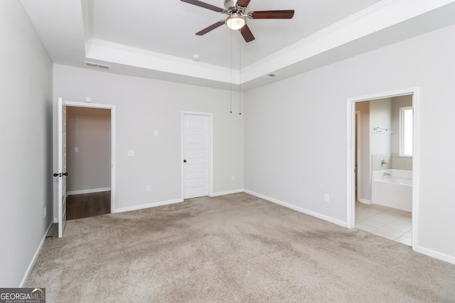 unfurnished bedroom featuring ornamental molding, a tray ceiling, light carpet, and visible vents