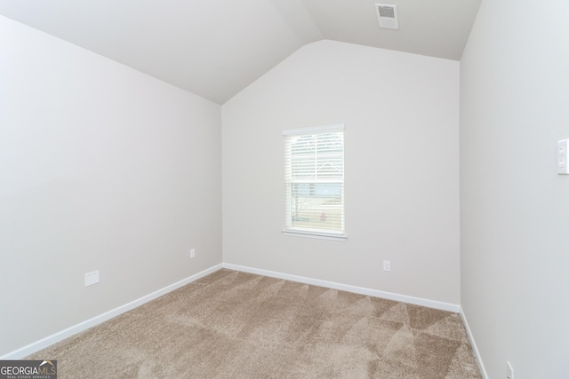 unfurnished room featuring visible vents, vaulted ceiling, light carpet, and baseboards