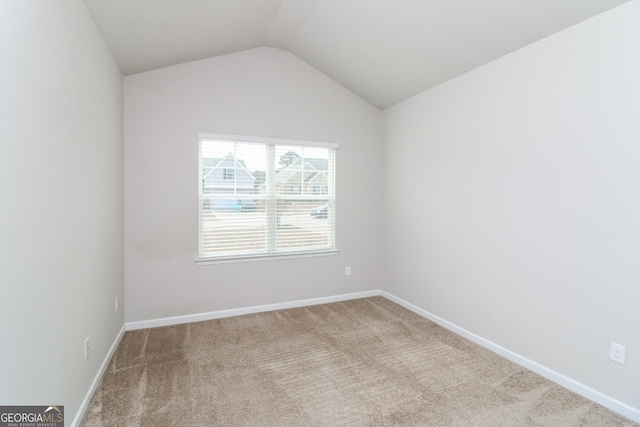 spare room featuring lofted ceiling, light carpet, and baseboards