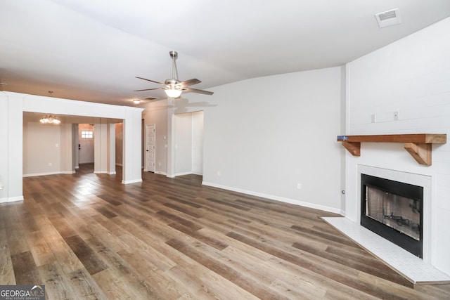 unfurnished living room featuring lofted ceiling, a large fireplace, visible vents, and wood finished floors