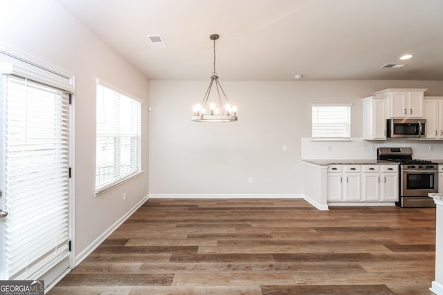 kitchen with a chandelier, stainless steel appliances, visible vents, white cabinets, and dark wood finished floors