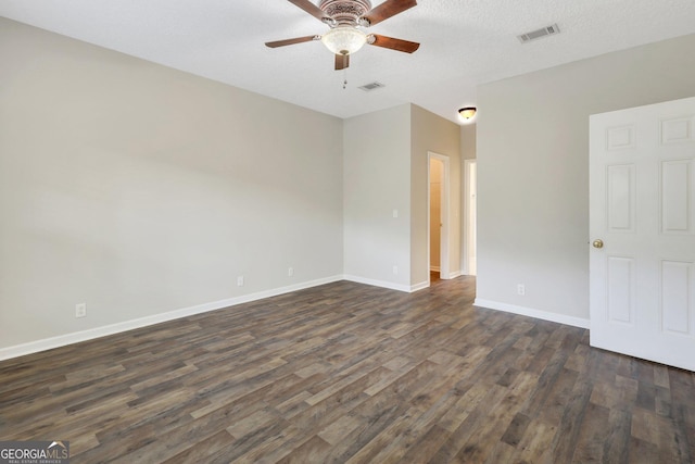 spare room featuring ceiling fan, a textured ceiling, visible vents, baseboards, and dark wood finished floors