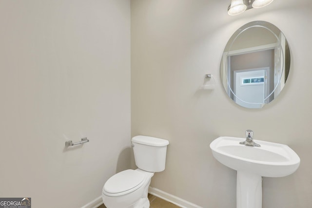 half bath featuring tile patterned flooring, baseboards, and toilet