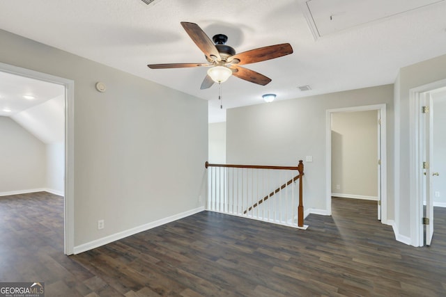 unfurnished room with dark wood-style floors, visible vents, attic access, ceiling fan, and baseboards