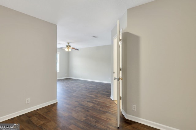 empty room featuring dark wood-style floors, visible vents, ceiling fan, and baseboards