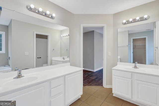 bathroom featuring tile patterned flooring, two vanities, a sink, and toilet