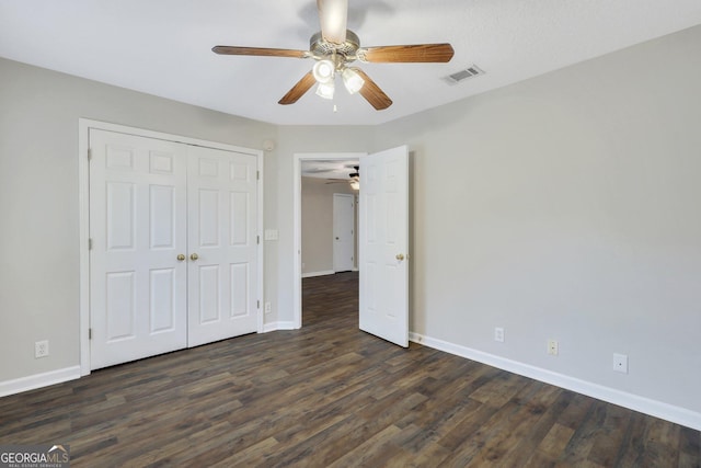 unfurnished bedroom with a closet, dark wood-style flooring, and baseboards