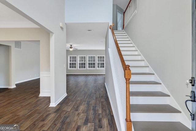 stairs featuring a ceiling fan, crown molding, visible vents, and wood finished floors