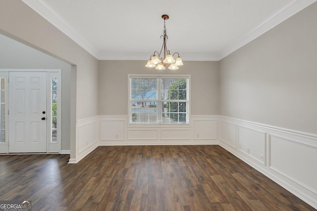 unfurnished dining area with crown molding, a wainscoted wall, dark wood finished floors, and a notable chandelier