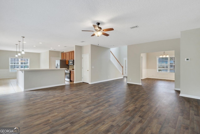 unfurnished living room featuring dark wood-style floors, visible vents, a textured ceiling, and ceiling fan with notable chandelier