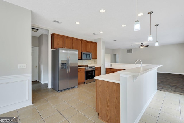 kitchen with brown cabinets, stainless steel appliances, light countertops, hanging light fixtures, and visible vents