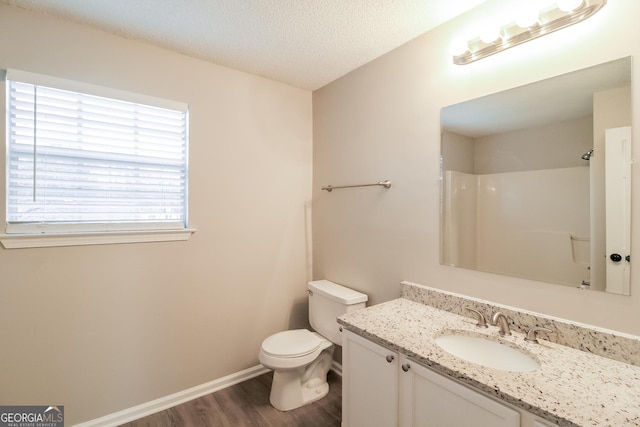 bathroom with toilet, wood finished floors, walk in shower, a textured ceiling, and vanity