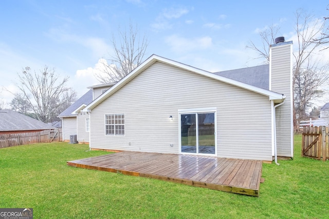 back of property with central AC unit, fence, a yard, a wooden deck, and a chimney