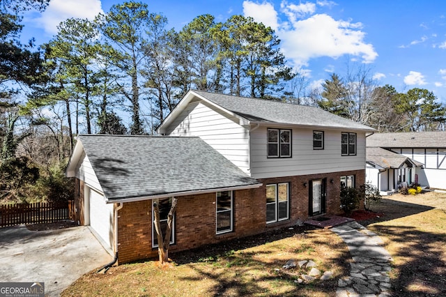 view of front of home featuring an attached garage, brick siding, a shingled roof, and fence