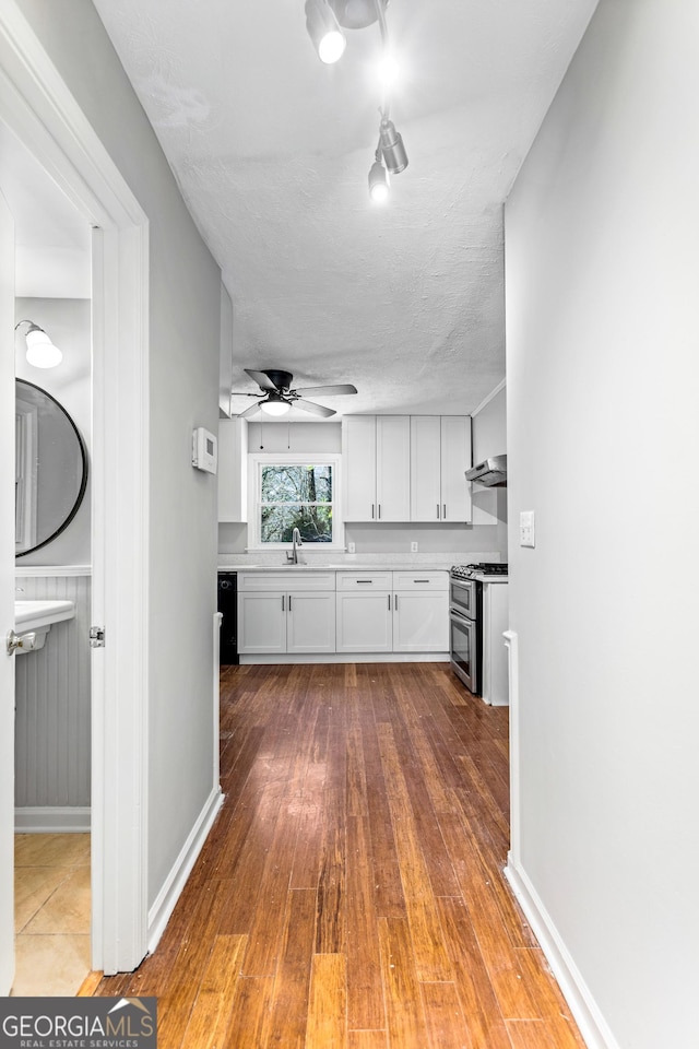 kitchen with range with two ovens, white cabinets, light countertops, dishwasher, and hardwood / wood-style floors