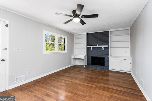 unfurnished living room featuring built in features, a brick fireplace, visible vents, and dark wood finished floors