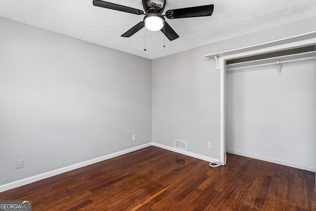 unfurnished bedroom with dark wood-style floors, a closet, visible vents, a textured ceiling, and baseboards