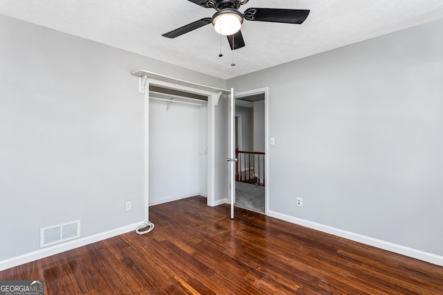 unfurnished bedroom with dark wood-style flooring, a closet, visible vents, and baseboards