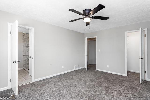 unfurnished bedroom featuring a textured ceiling, visible vents, and carpet flooring