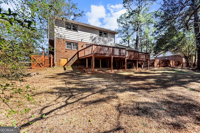 back of property featuring a wooden deck, stairs, fence, a yard, and brick siding