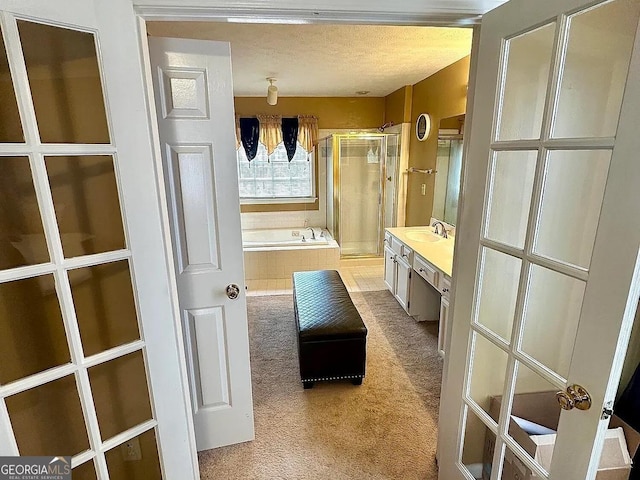 full bathroom featuring french doors, a shower stall, a textured ceiling, vanity, and a bath