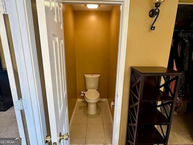 bathroom featuring tile patterned flooring, baseboards, and toilet