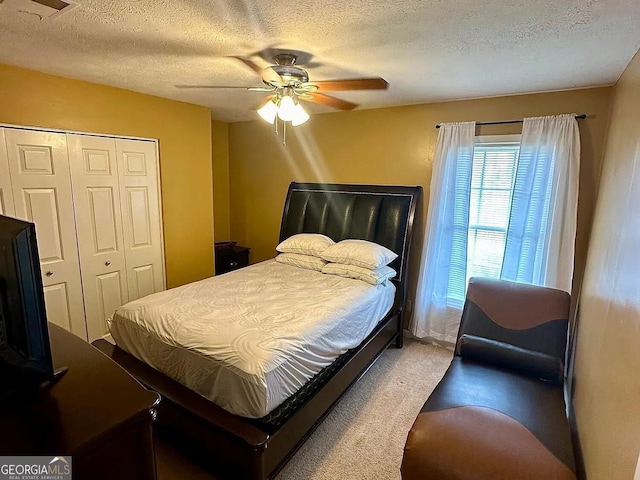 bedroom with carpet, a textured ceiling, a ceiling fan, and a closet