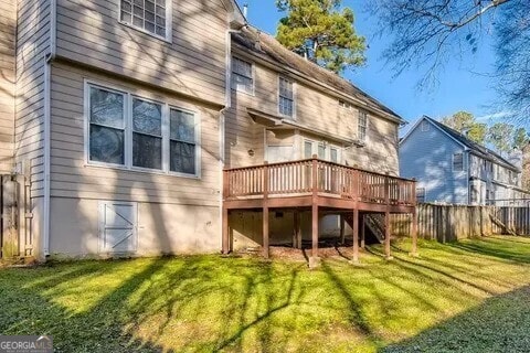 rear view of property with a yard, fence, and a deck