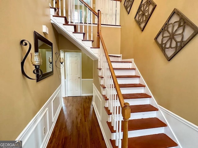 stairs featuring a high ceiling, wood finished floors, and baseboards