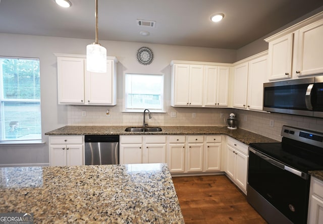 kitchen with stainless steel appliances, dark stone counters, and a sink