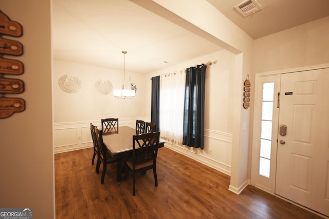 dining room with dark wood-type flooring, wainscoting, visible vents, and an inviting chandelier